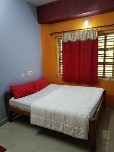a bedroom with a bed with a red curtain at Budget Friendly Rooms in Coorg in Jāmb