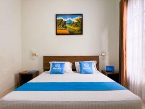 a bedroom with a large bed with blue pillows at Adiputra Guesthouse Tata Bumi by HomiQ in Yogyakarta