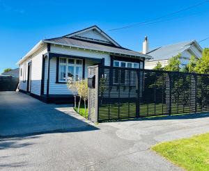 a house with a black fence in front of it at Pretty Villa Close to St Clair Beach private parking in Dunedin