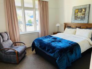 a bedroom with a bed and a chair and a window at Pretty Villa Close to St Clair Beach private parking in Dunedin