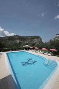 a large swimming pool with chairs and umbrellas at Hotel Villa Verde in Nago-Torbole