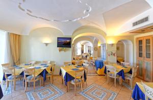 a restaurant with yellow tables and blue chairs at Hotel Punta Imperatore in Ischia