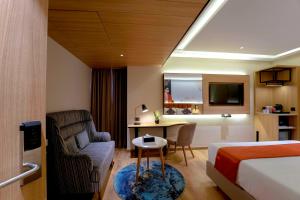 ein Hotelzimmer mit einem Bett, einem Stuhl und einem Schreibtisch in der Unterkunft TGI Oberon in Bangalore