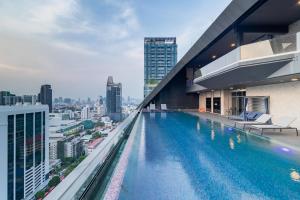 a swimming pool on the roof of a building with a city at Queensland Hotel Bangkok in Bangkok