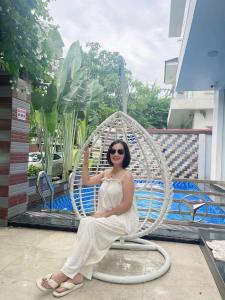 een vrouw zit op een metalen stoel bij Villa NT119 FLC Sầm Sơn in Sầm Sơn