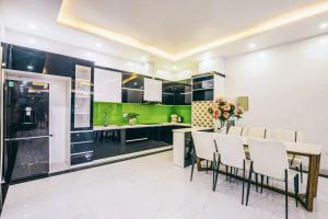een keuken met een eettafel en een groene muur bij Villa NT119 FLC Sầm Sơn in Sầm Sơn