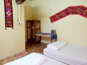 Una habitación con dos camas y una mesa dentro. en Mai Tiến homestay 188, en Mai Chau