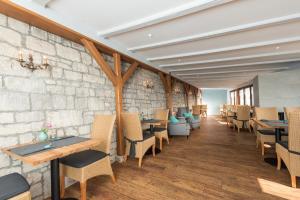 ein Restaurant mit Tischen und Stühlen und einer Steinmauer in der Unterkunft Berghotel Wilhelmsburg in Bad Kösen