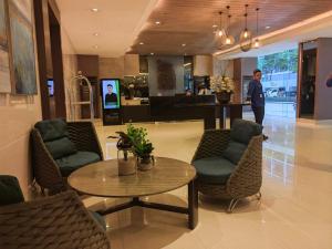 马尼拉La Vie Riche Holiday Homes - Cozy 1BR Apartment near MOA的站在大堂的男人,手里拿着桌子和椅子