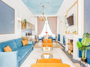 salon z niebieską kanapą i pomarańczowymi krzesłami w obiekcie Merveil - Luxury Suite -Champs Elysees-Haussmann I w Paryżu