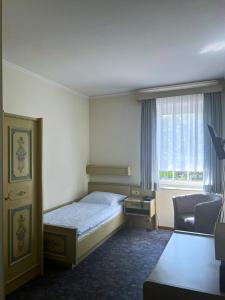 a bedroom with a bed and a chair and a window at Rodes Hotel und Restaurant in Rehburg-Loccum