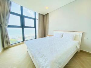 a bedroom with a white bed with a large window at Căn hộ du lịch 2 phòng ngủ Aria Vũng Tàu Hotel & Villa Resort, Hồ bơi và bãi tắm riêng miễn phí, 30m ra biển in Vung Tau +20 photos