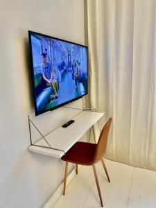 TV en la pared con mesa y silla en Katas Suite, Helsinki city center, en Helsinki