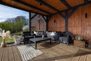 a living room with couches and a table on a deck at Widokownia Bukowinki 2 in Chmielno