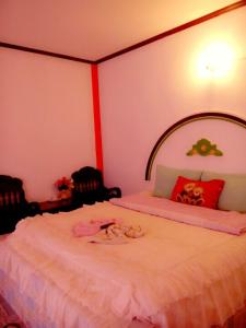 a bedroom with a large white bed with two chairs at Jidapha Rooms in Khlong Thom