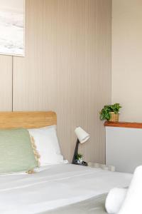 シドニーにあるComfortable Single Room in Convenient Belmore Location - Shared Bathroomのベッドルーム1室(白いベッド1台、ランプ、植物付)