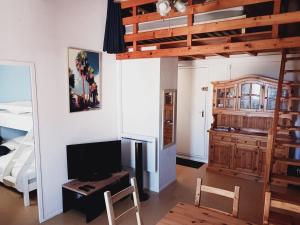a living room with a loft bed and a television at Le Sun Piscine Tennis parking Vue mer wi-fi climatisation in Fleury