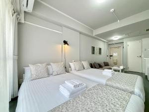 Un dormitorio blanco con dos camas y un sofá. en Neighbor's Hotel 西十日市, en Hiroshima