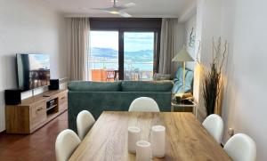 un soggiorno con tavolo e divano verde di Holibai, Son do Mar Son do Mar, Lujo sereno frente al Atlántico, Baiona a Baiona