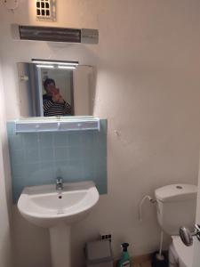 un homme prenant une photo d'une salle de bains avec lavabo dans l'établissement T1 dans immeuble sur plage, au Grau-du-Roi