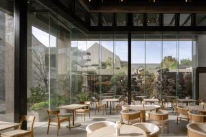 a restaurant with tables and chairs and large windows at 扬州广陵有熊酒店 in Yangzhou