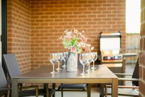 a table with wine glasses and a vase of flowers at New family-friendly home in Melton South