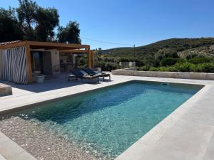a swimming pool with a patio and a house at Sunny Villas in Klísmata