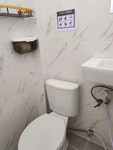 ein weißes Badezimmer mit Toilette und Waschbecken in der Unterkunft Omber Inn in Supadio