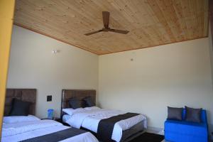 a bedroom with two beds and a ceiling fan at Hotel An Himalayan View in Barkot +26 photos