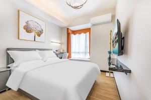 a bedroom with a white bed and a television at 漫点 Moodlink Hotel at Taikoo Hui, Sports Center in Guangzhou