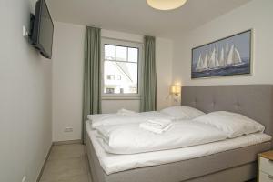 ein Schlafzimmer mit einem großen weißen Bett mit einem Fenster in der Unterkunft Rex Rugia FeWo12-2 strandnah,Terrasse,Sauna,Pool in Lobbe + 20 Fotos