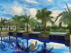 a swimming pool with palm trees and blue water at Torre De Manila in Manila