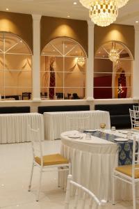 una sala da pranzo con tavoli e sedie bianchi e un lampadario di Hotel Mahadev Villa Elite a Jaipur