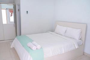 a white bed with two rolled up towels on it at Griya Safitri Syariah in Palembang