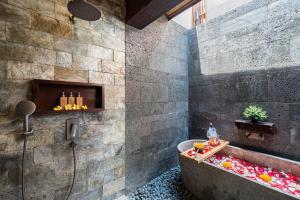 a bathroom with a stone wall and a bath tub at Villa Dijabu in Kuta
