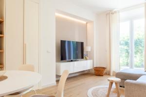 a living room with a tv on a white cabinet at Charming staying by the sea in Rosignano Solvay