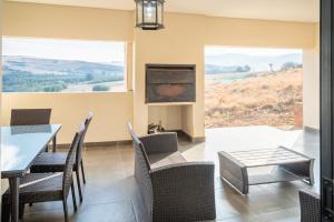 Un comedor con mesa y sillas y una gran ventana. en 910 Highland Gate Golf & Trout Estate, en Dullstroom
