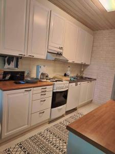 une cuisine avec des armoires blanches et un four à plaques de cuisson dans l'établissement Cozy Forest Retreat in Kuopio - Perfect for Families Work Trips, à Kuopio