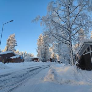 une rue enneigée avec un arbre et une maison dans l'établissement Cozy Forest Retreat in Kuopio - Perfect for Families Work Trips, à Kuopio
