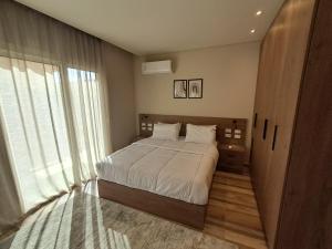 a bedroom with a bed and a large window at شقة فندقية فى الشيخ زايد داخل كمبوند حديقة خاصة ومدخل خاص in Sheikh Zayed