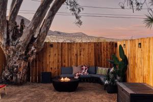 a patio with a couch and a tree in front of a fence at Modern Sunset in Yucca Valley