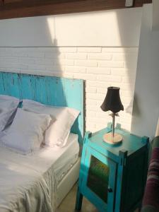 niebieskie łóżko z niebieskim stołem i lampą na nim w obiekcie Rumah Kayu Yogyakarta By Hamsa Putih w mieście Yogyakarta