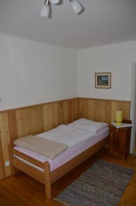 Bett in einem hölzernen Zimmer mit einem Nachttisch und einem Bett der Marke sidx sidx sidx. in der Unterkunft Haus Rosina in Admont