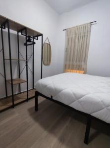 a bedroom with a bed with white sheets and a window at La Casita de Cullera in Cullera