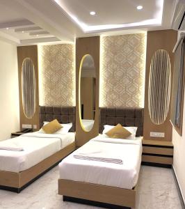 two beds in a hotel room with a mirror at UPTOWN Inn in Bengaluru