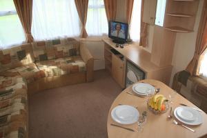 a living room with a table, chairs and a television at Dinas in Llanbedr
