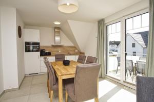 Una cocina y un comedor con mesa y sillas de madera. en Rex Rugia FeWo12-5 mit Schwimmbad und Saunanutzung im AHOI-Erlebnisbad Sellin, en Lobbe