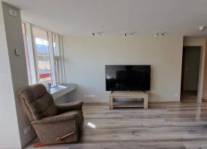 a living room with a television and a chair at Hunavellir Guesthouse in Blönduós