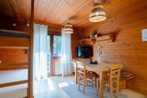 a dining room with a table and chairs and a television at Forest Apartments POKLJUKA in Zgornje Gorje