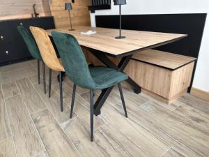 a wooden table with green chairs in a room at Zalona Altitude Appartement T3 - Emplacement exceptionnel - entrée indépendante - entièrement rénové in Tignes